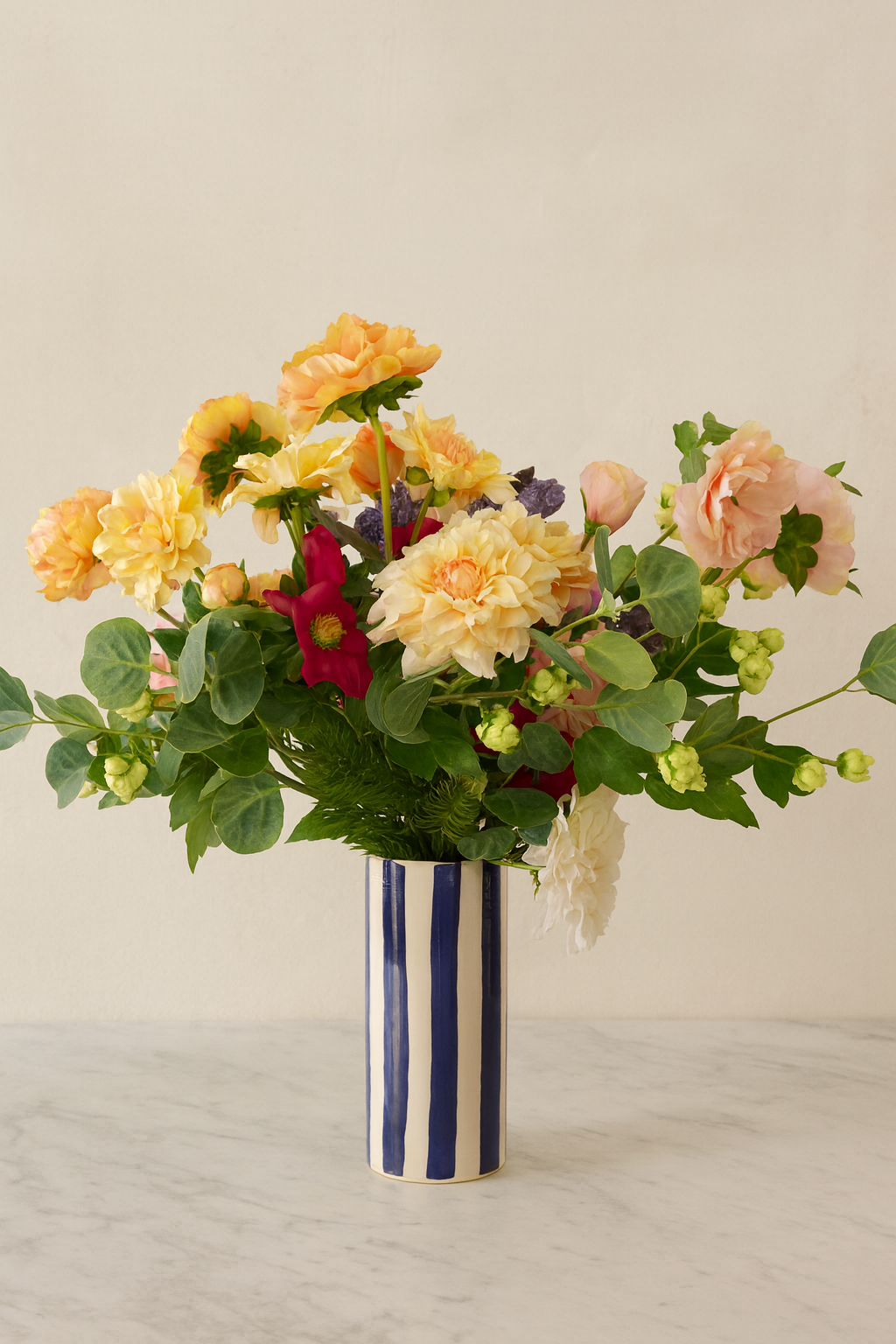 Composition Studio XL — dahlia jaune, hellébore et houblon dans vase rayé bleu