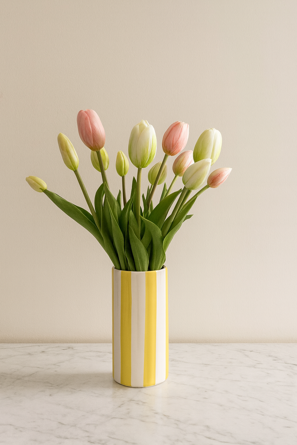 Bouquet de tulipes rose et blanc dans vase rayé jaune